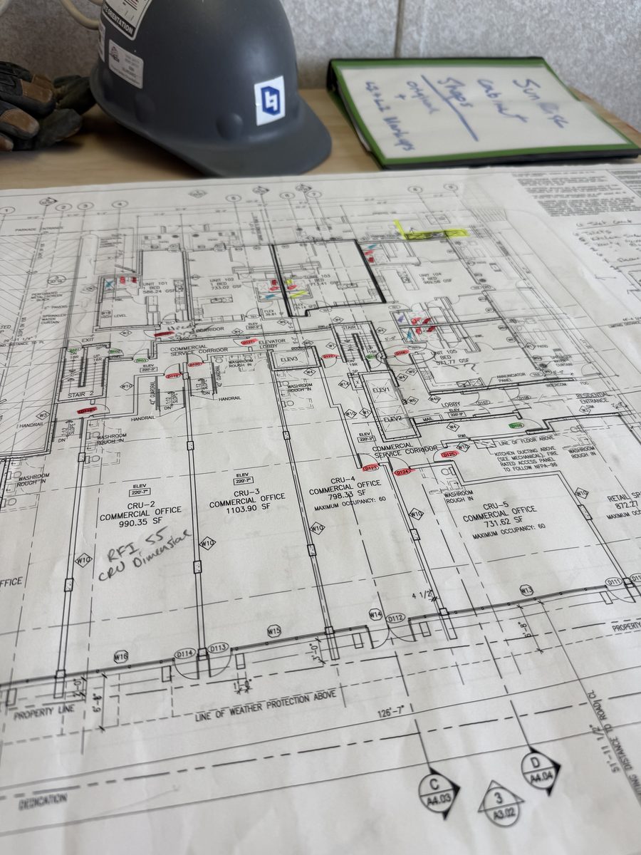 Hard hat resting on a marked-up construction drawing set