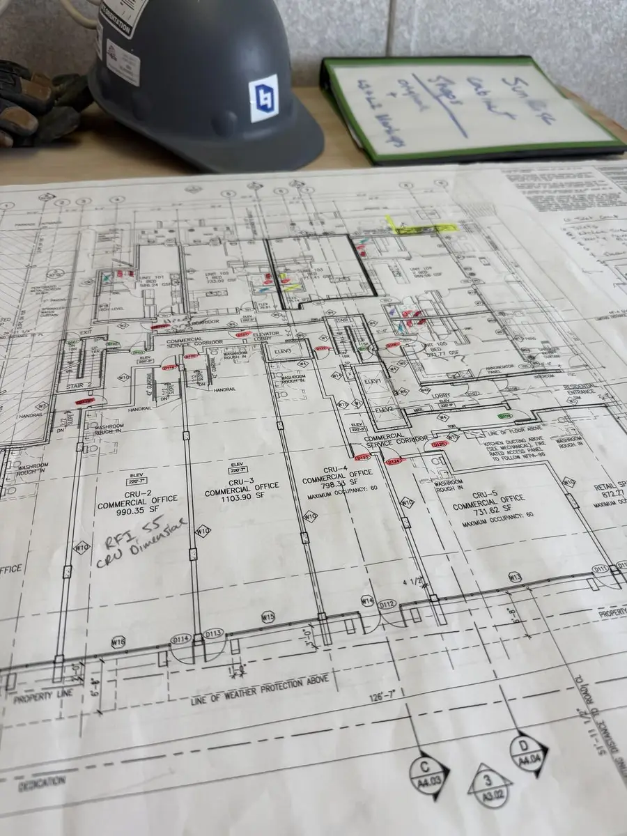 Hard hat resting on a marked-up construction drawing set
